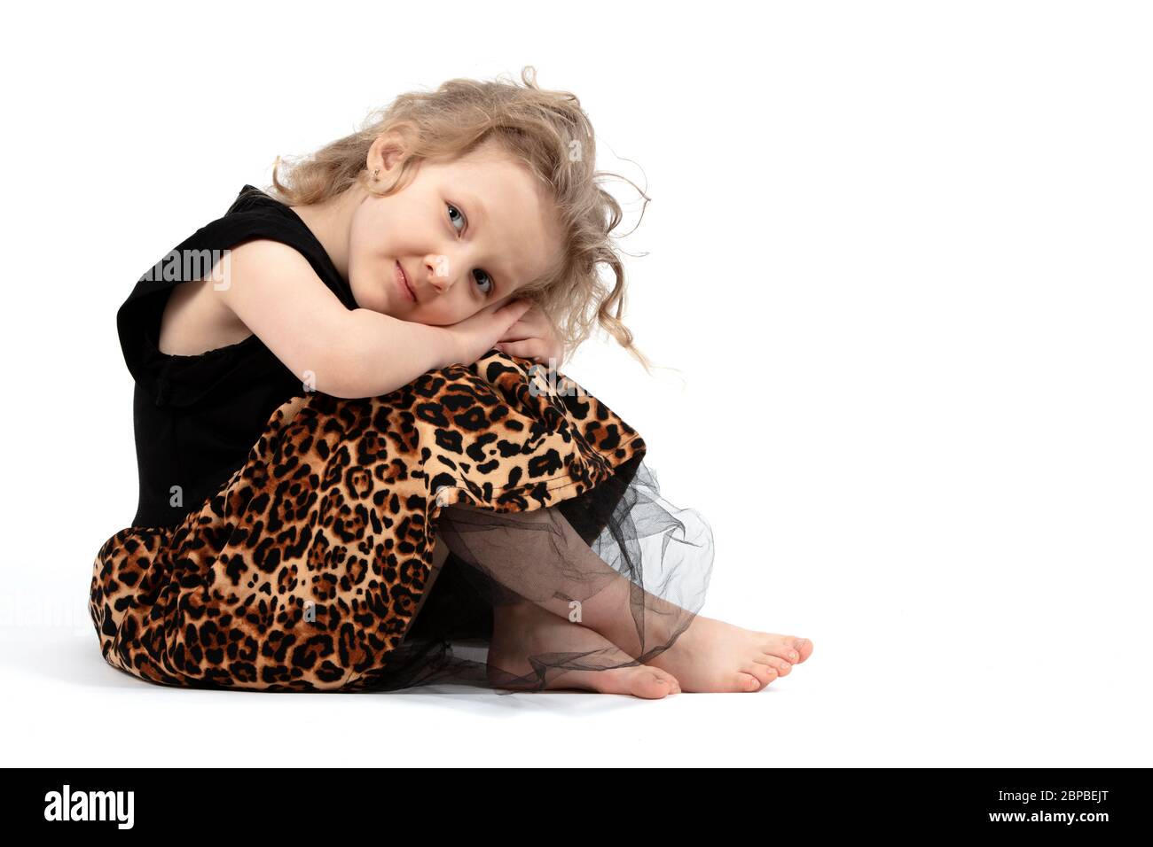 Ziemlich Baby. Kleines blondes Mädchen auf weißem Hintergrund. Ein vierjähriges Kind sitzt auf den Knien. Stockfoto