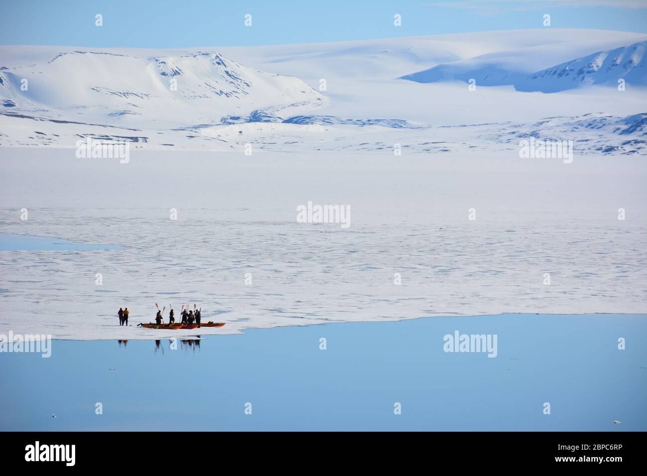 Touristen auf einer Expeditionskreuzfahrt nehmen im Sommer an einer Kajakfahrt in einer geschützten Bucht in Svalbard, norwegischer Arktis, Teil. Stockfoto