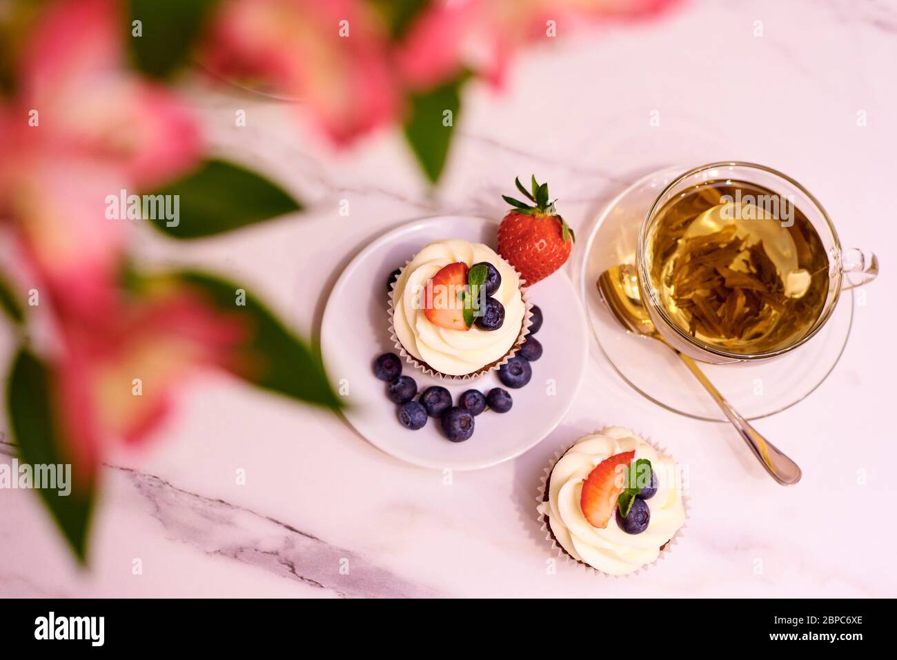 Cupcakes mit Erdbeeren und Heidelbeeren. Cupcakes mit einer Tasse Tee. Selektiver Fokus. Stockfoto