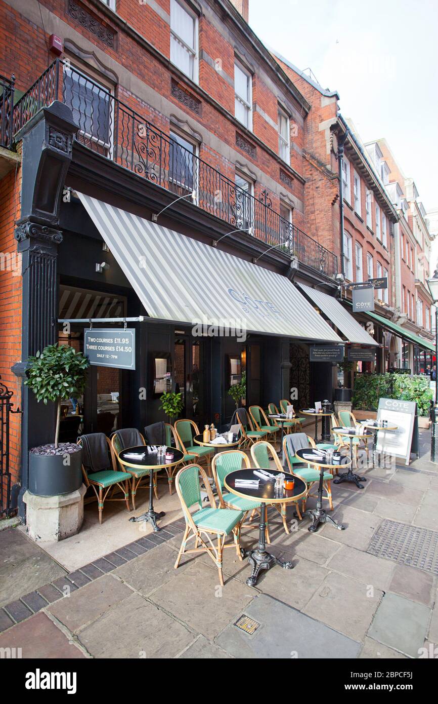 Côte Bistro, Blick auf Straßenebene auf ein stilvolles Café mit schwarzem Markise und Korbstühlen auf dem Bürgersteig, Kensington Stockfoto