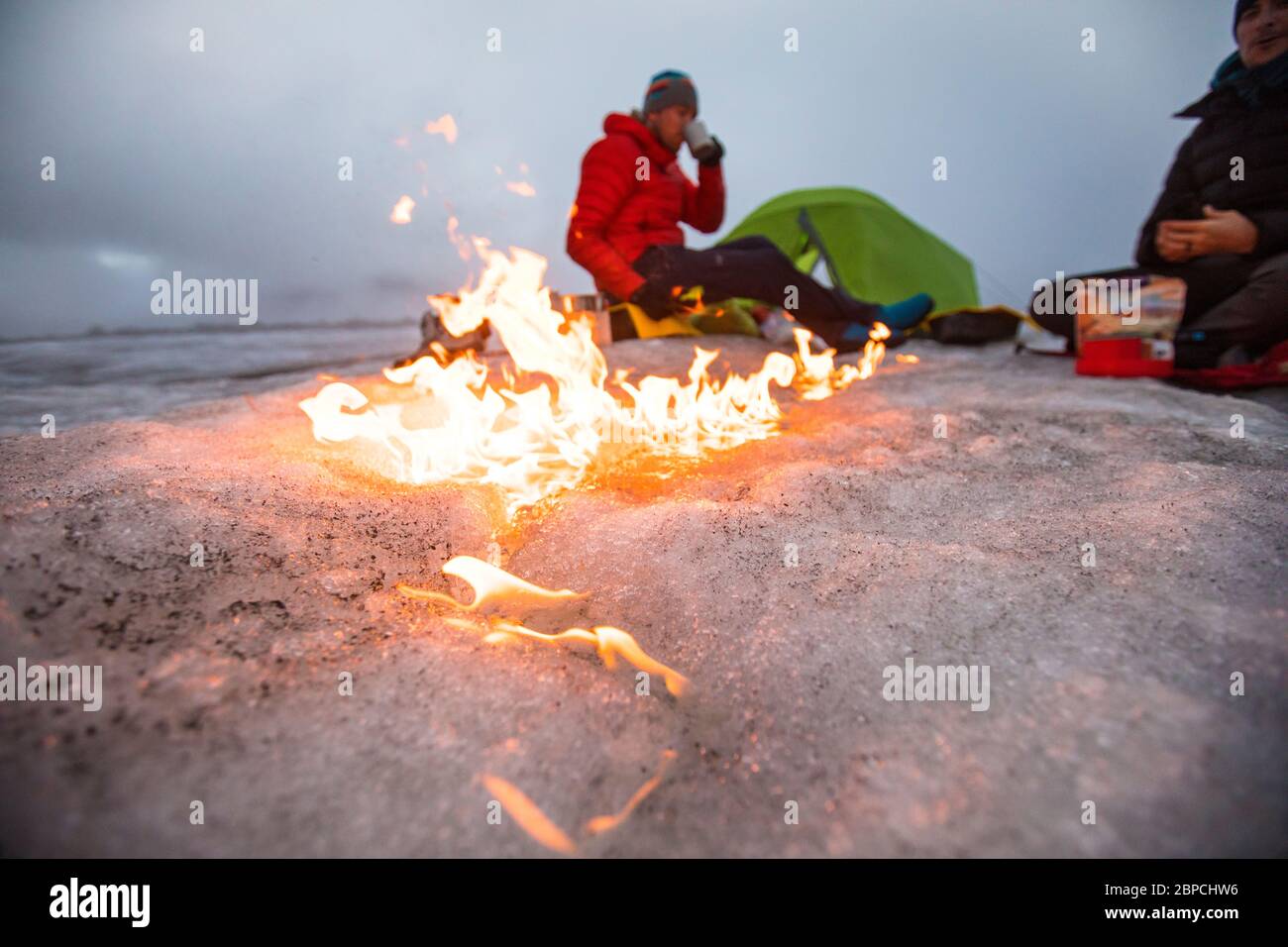 Lagerfeuer bewegt sich über den Gletscher, als zwei Männer auf einem Gletscher zelten. Stockfoto