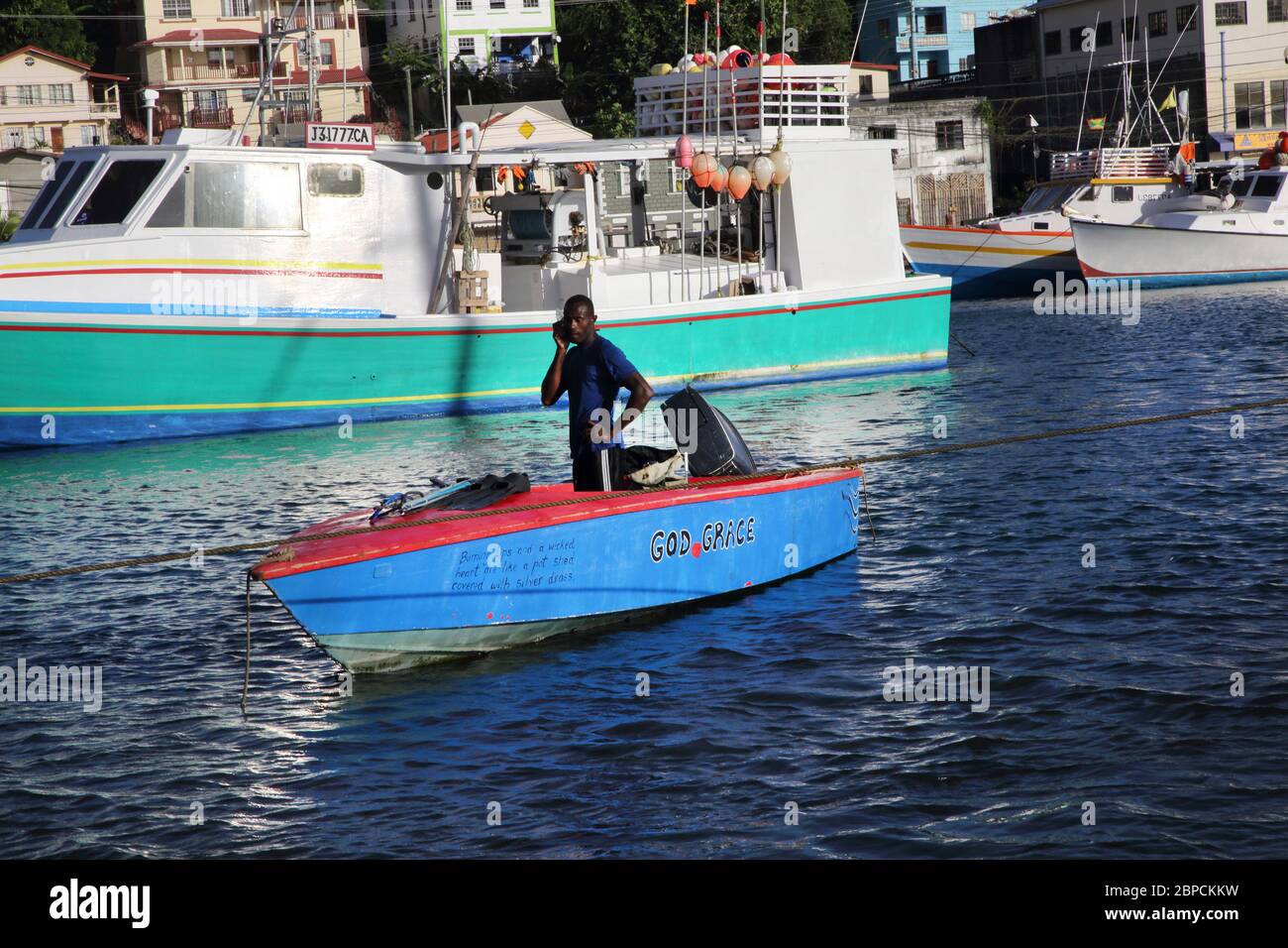 St George's Grenada Carenage Harbour man im kleinen Boot mit Angelschnur auf dem Handy sprechen Stockfoto