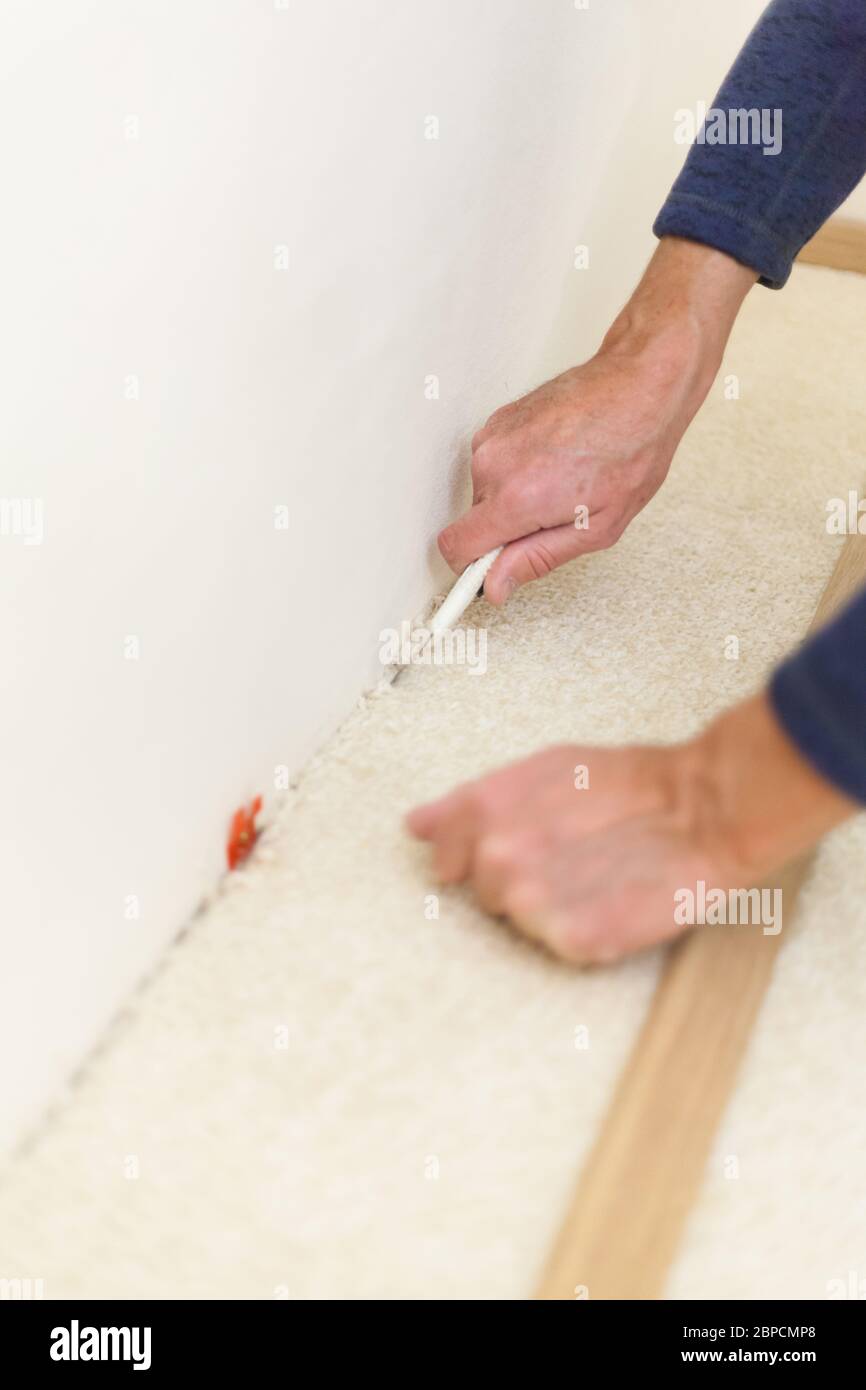 Handwerker Schnitte mit Teppich Messer Gelenke für Holzleisten Sicherheitsmesser renovieren Rücken Schmerzen Bodenbelag Stockfoto