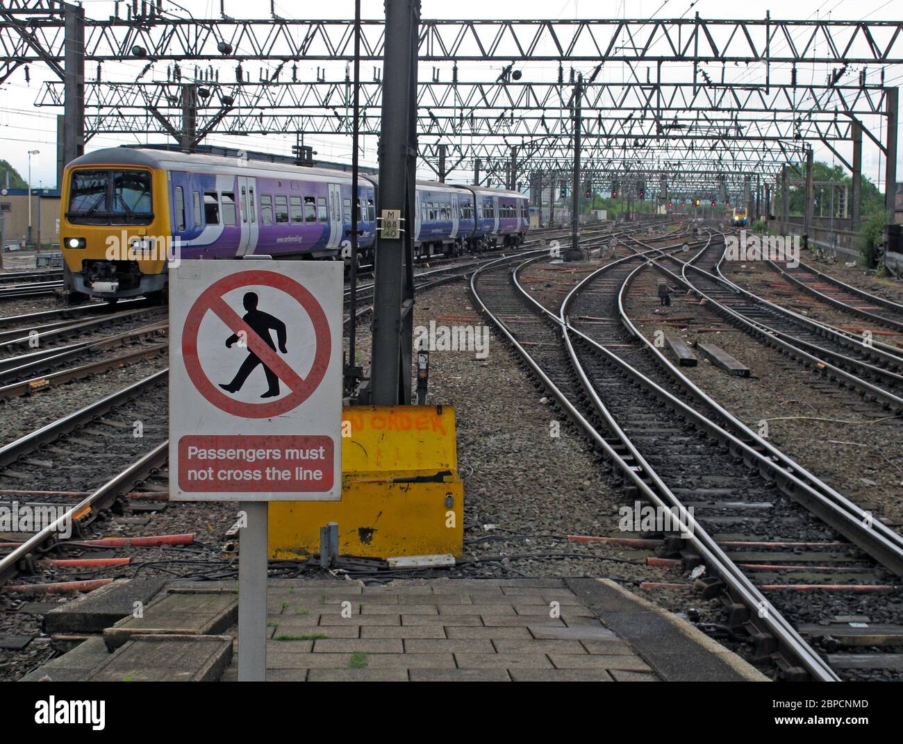 Bahnpassagiere dürfen nicht die Linie Zeichen überqueren, Northern Rail Zug Stockfoto