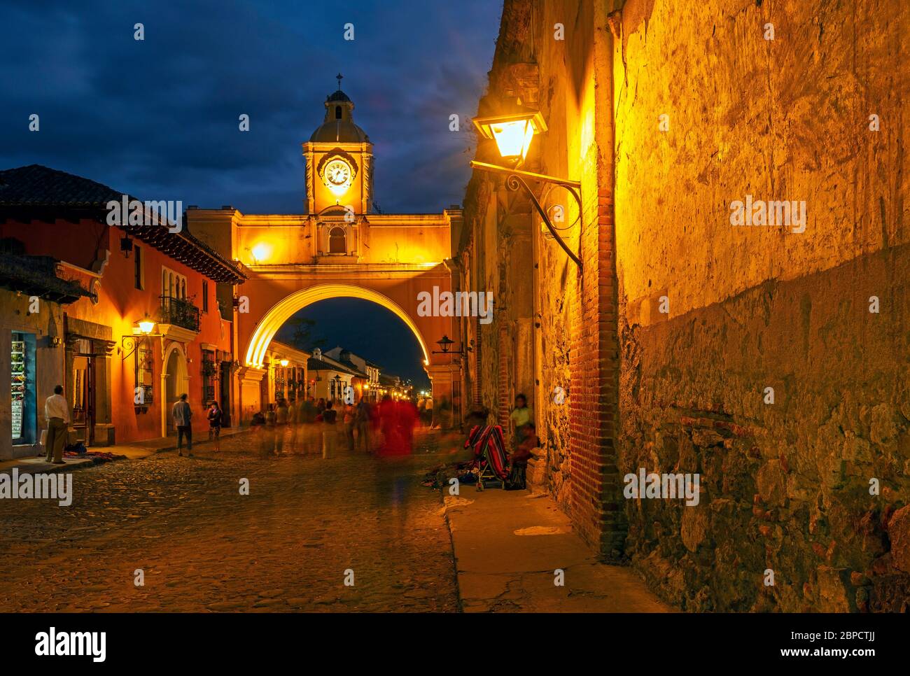 Langzeitbelichtung Stadtbild des Santa Catalina Arch bei Nacht mit verschwommenen Bewegungen der Menschen in Antigua, Guatemala. Stockfoto