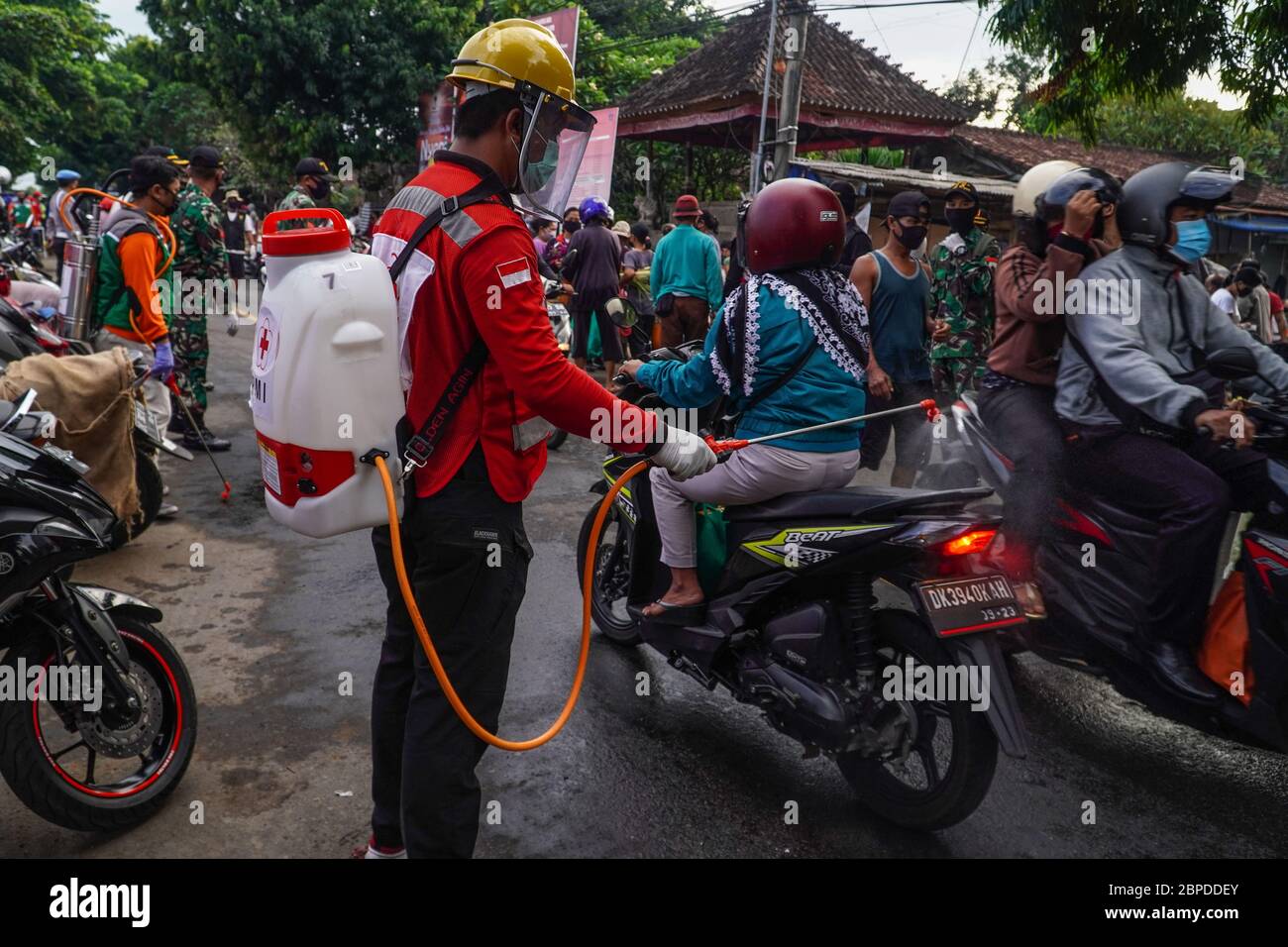 Gianyar, Bali, Indonesien. Mai 2020. Ein Mann vom indonesischen Roten Kreuz sprüht Desinfektionsmittel auf ein vorbeifahrender Motorrad. Die Task Force bildet die traditionellen Markthändler von Sukawati aus dem Covid-19 Coronavirus Gesundheitsprotokoll in Gianyar, Bali, Indonesien. Kredit: Dicky Bisinglasi/ZUMA Wire/Alamy Live News Stockfoto