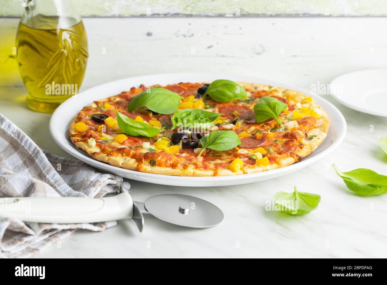 Leckere Salami-Pizza. Pizza mit Basilikumblättern auf dem Teller. Stockfoto