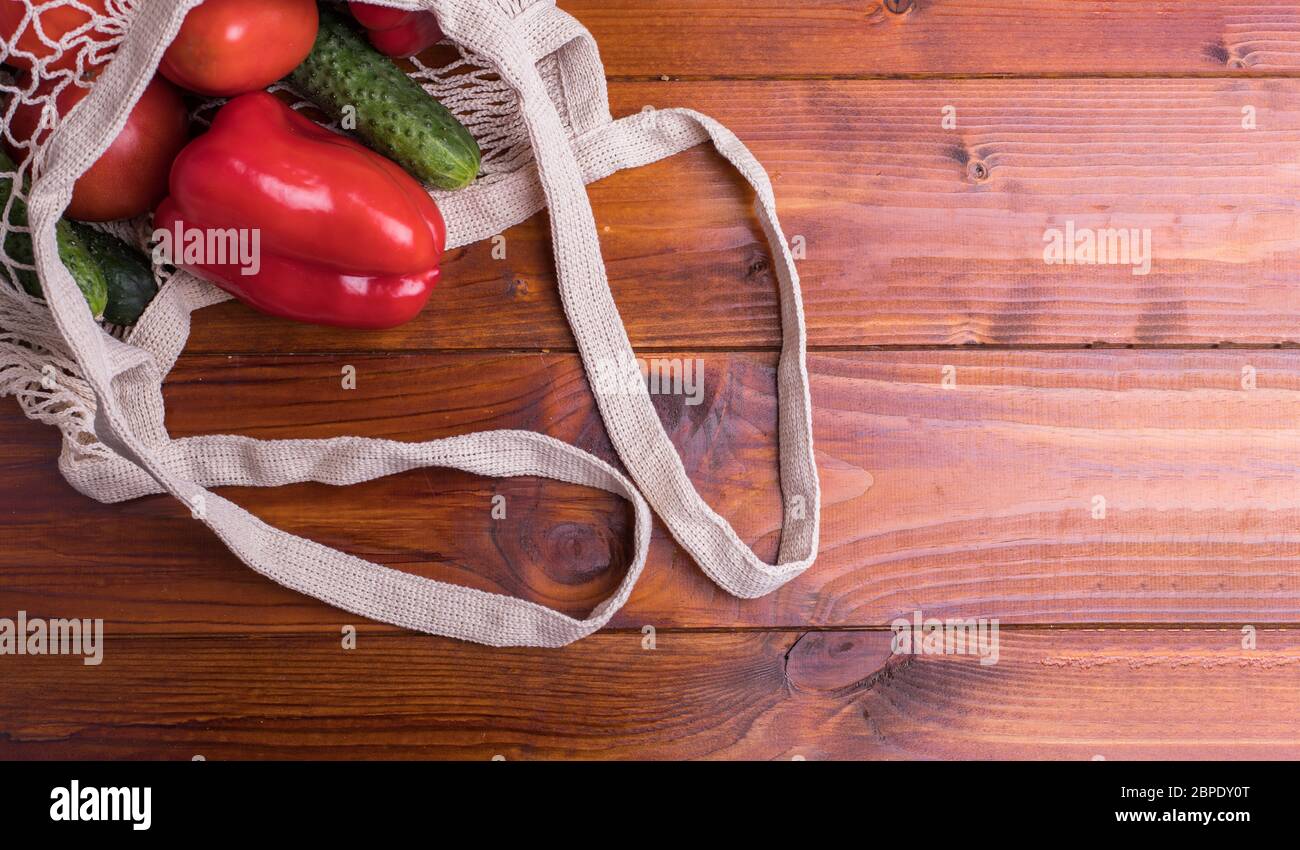 Eco Beutel Saite Beutel mit Gemüse Gurken und Tomaten auf einem Holzhintergrund. Zero West Flat Lay, Draufsicht Stockfoto
