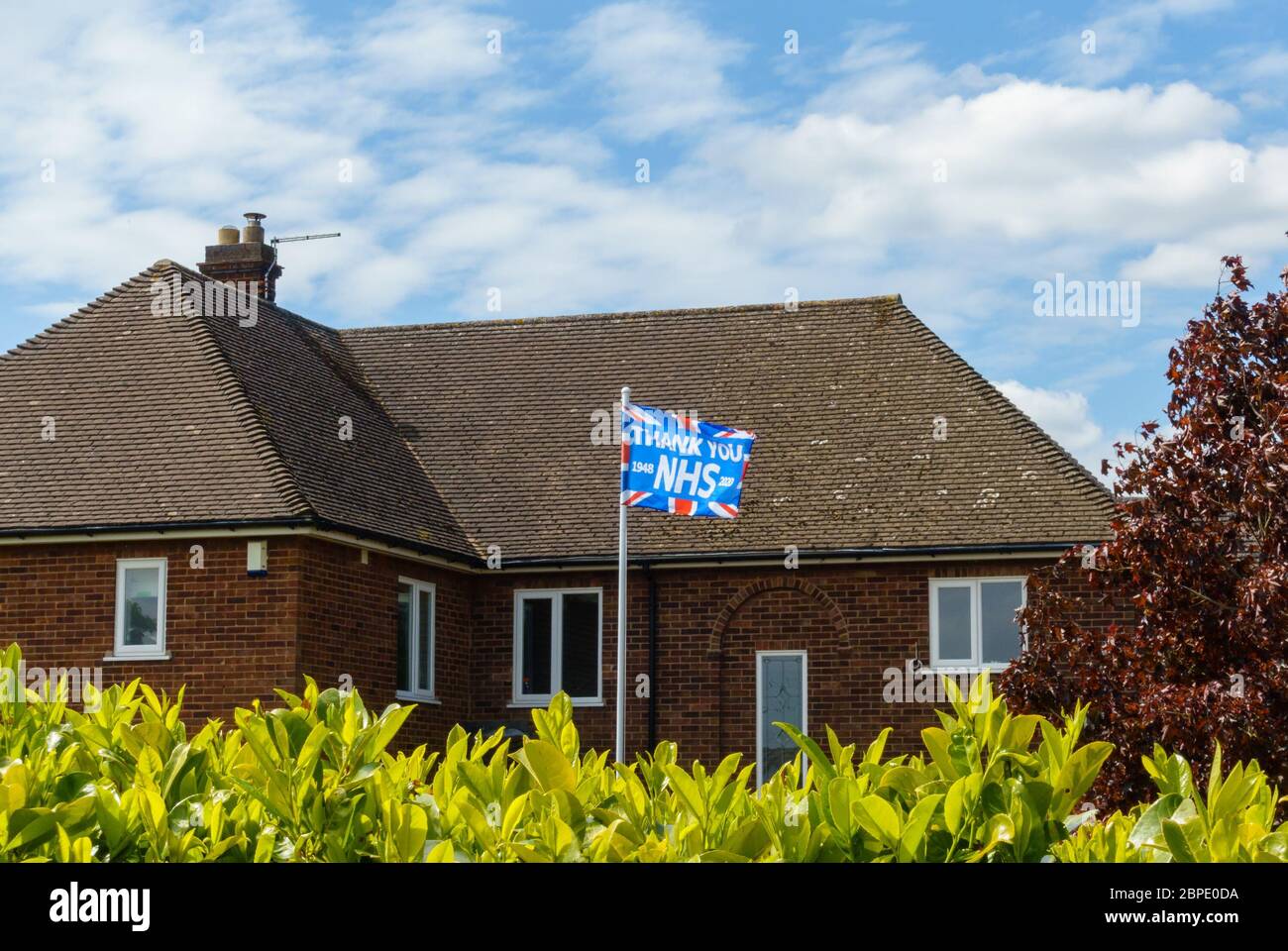 "Danke NHS"-Gewerkschaftsflagge, die auf Fahnenmast vor dem Haus fliegt, um dem NHS während der Coronavirus-Pandemie im Mai 2020 in England zu danken Stockfoto