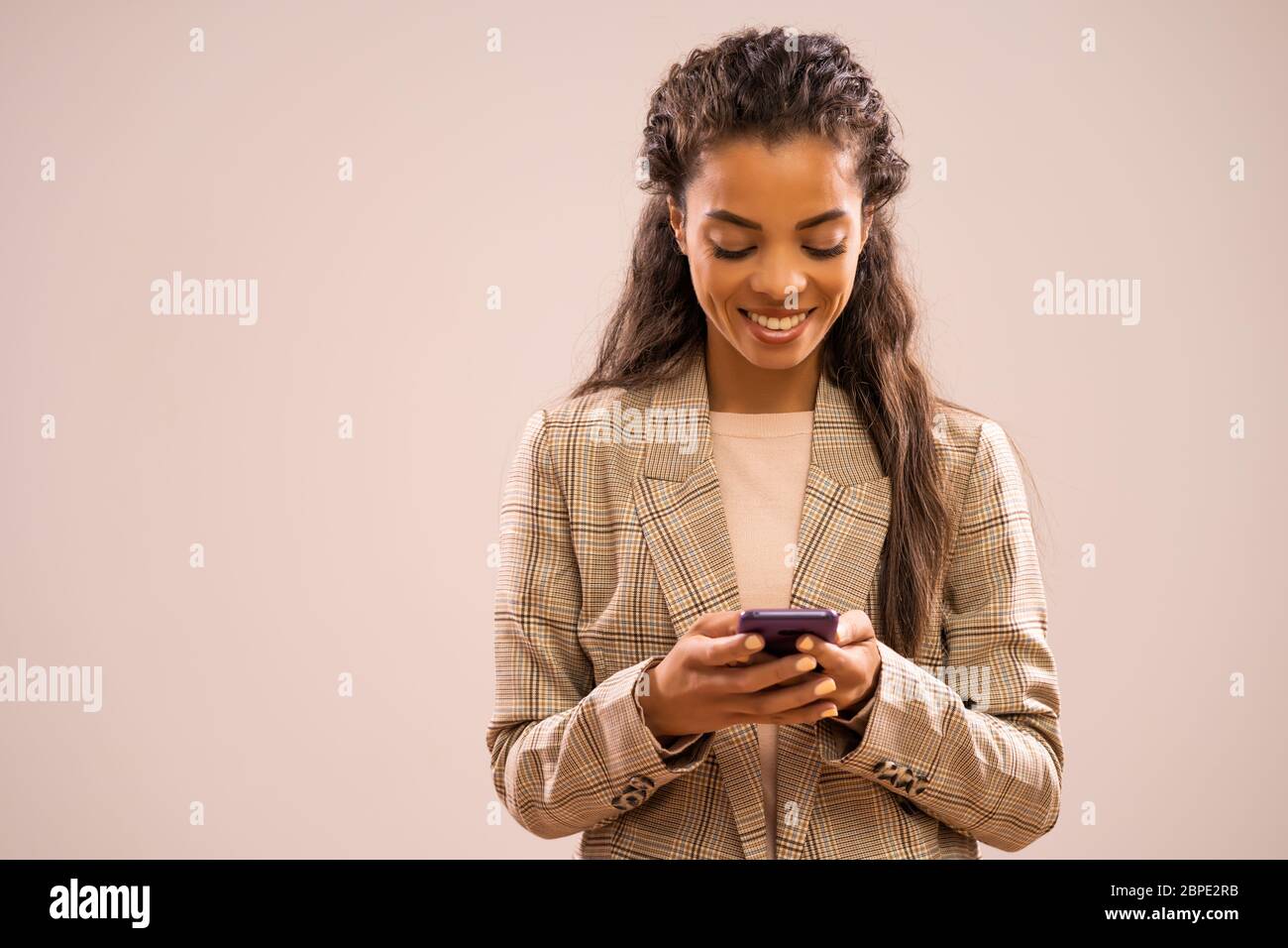 Studio-Aufnahme Porträt der schönen glücklichen afroamerikanischen Ethnizität Geschäftsfrau mit Smartphone. Stockfoto