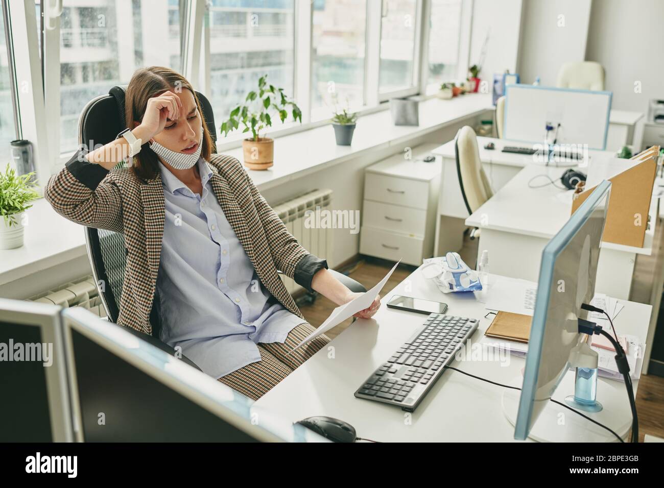 Frustrierte junge Geschäftsfrau, die während des Coronavirus aus Vertragsproblemen im leeren Büro gestresst wird Stockfoto