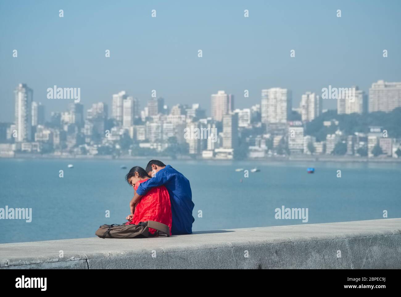 Ein junges Teenager-Paar, das sich auf dem Damm am Marine Drive am Arabischen Meer in Mumbai, Indien, umarmt Stockfoto