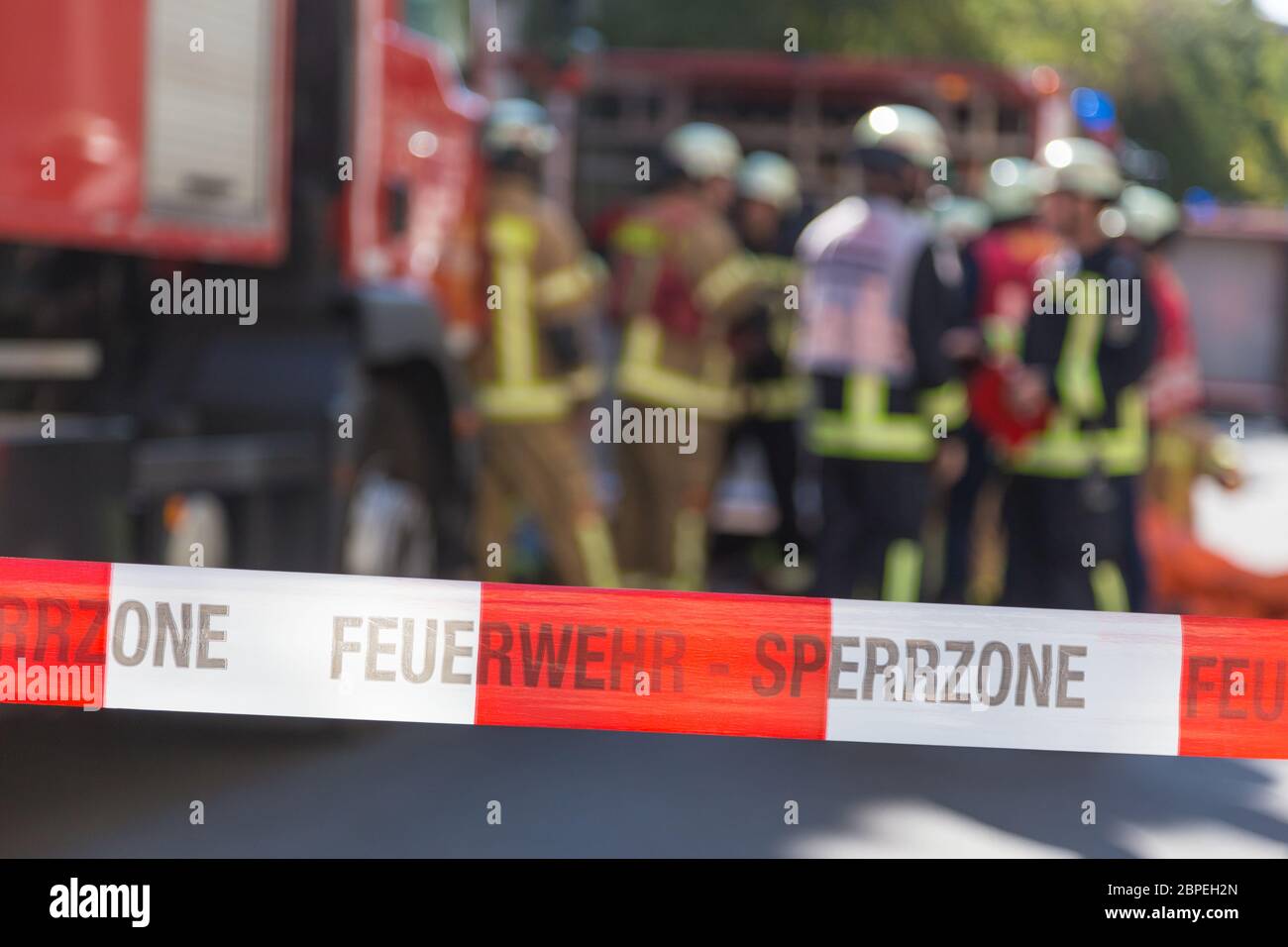 Team von blured Feuerwehrmänner, die durch firetruck auf geschützten Unfallstelle. Fokus auf roten und weißen Sicherheit band. Stockfoto
