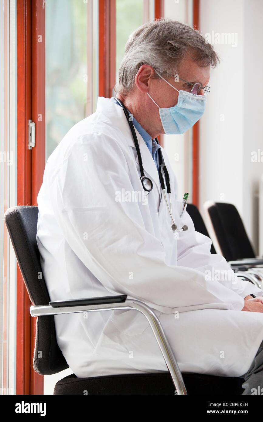 Müde oder erschöpfte Arzt sitzt in einem hellen Wartezimmer eines Krankenhauses oder einer Klinik - konzentrieren Sie sich auf das Gesicht Stockfoto