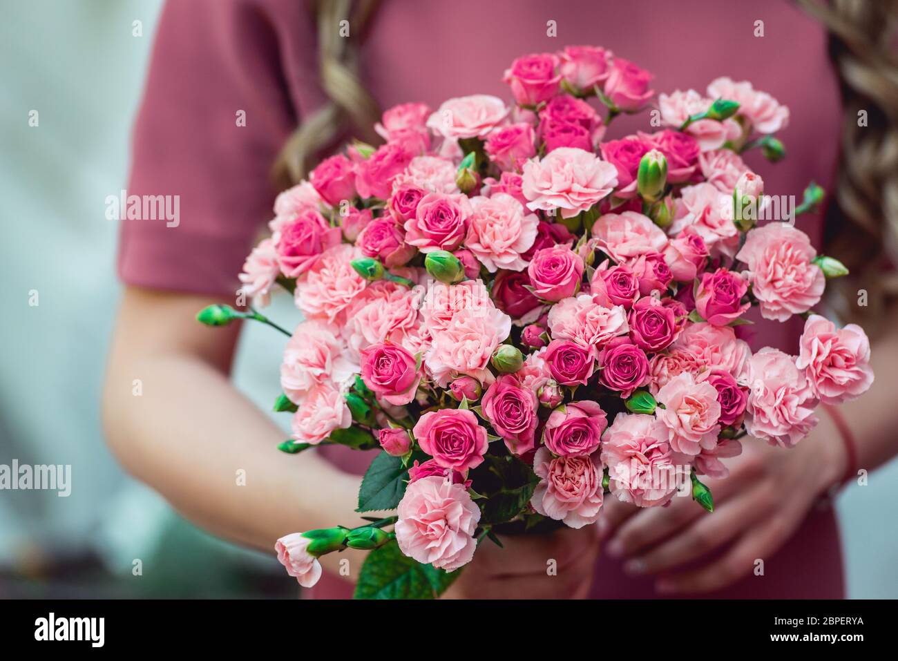 Frau in einem Kleid hält Hochzeit Blumensträuße von biege Nelken und rosa Rosen Stockfoto