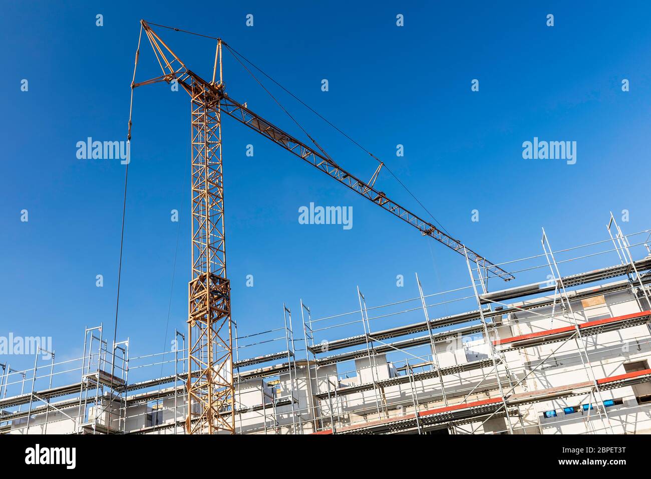 Baukran vor einem Neubau mit strahlend blauem Himmel Stockfoto