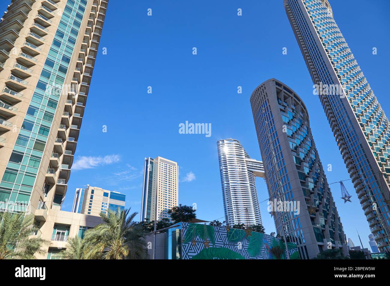 DUBAI, VEREINIGTE ARABISCHE EMIRATE - 23. NOVEMBER 2019: Moderne Wolkenkratzer mit Palmen im Finanzviertel, klarer blauer Himmel in Dubai Stockfoto