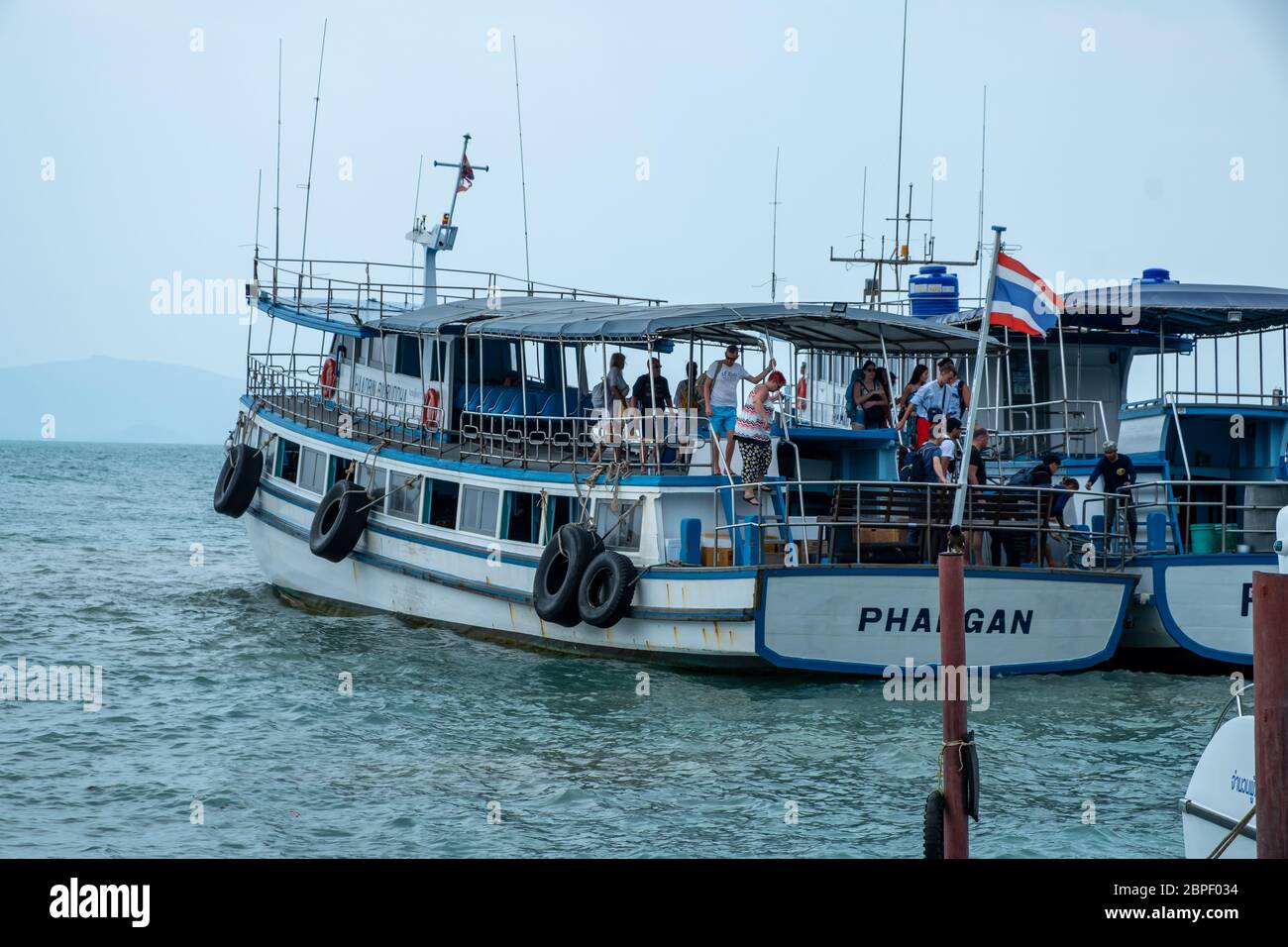 Ko Pha-ngan / Thailand - Februar 2020: Tropischer Inselpier mit Touristen und Boot. Touristen warten auf die Haad Rin Queen Fähre bei Haad Rin Stockfoto