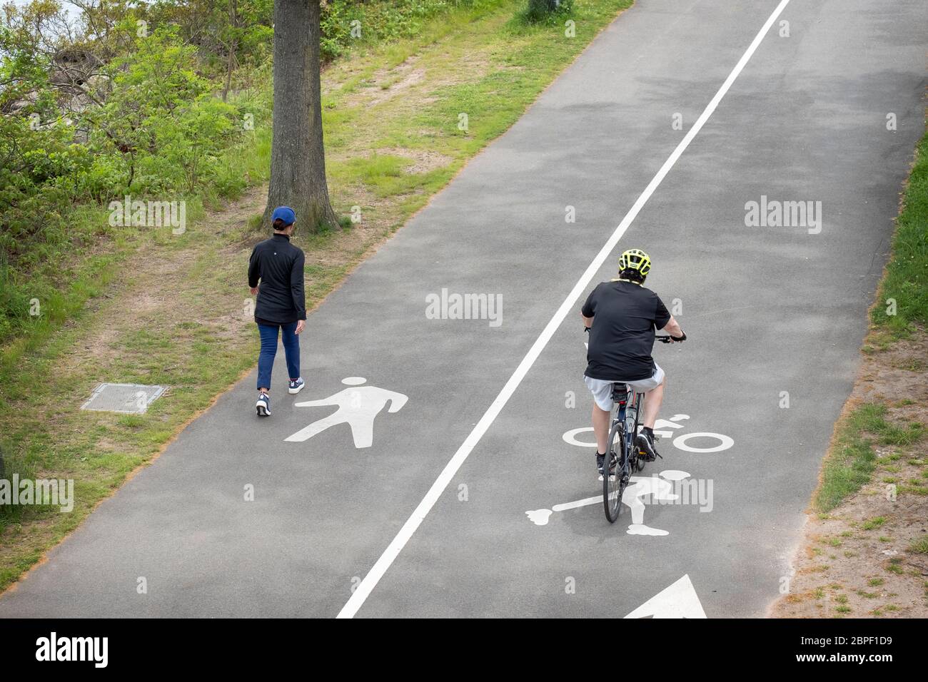 COMPLIANCE. Ein Wanderer und ein Biker trainieren jeweils in ihren ausgewiesenen Bahnen. In der Nähe des Jachthafens Bayside in Queens, New York City. Stockfoto