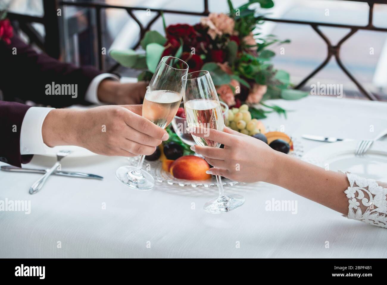 Gläser mit Champagner-Drink in Brautpaares. Fröhliches frisch vermähltes Trinken. Liebevolles Paar schuf neue Familie. Stockfoto