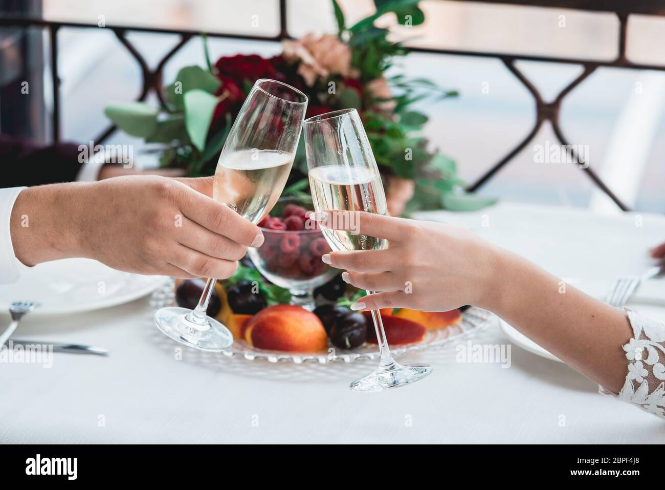 Gläser mit Champagner-Drink in Brautpaares. Fröhliches frisch vermähltes Trinken. Liebevolles Paar schuf neue Familie. Stockfoto