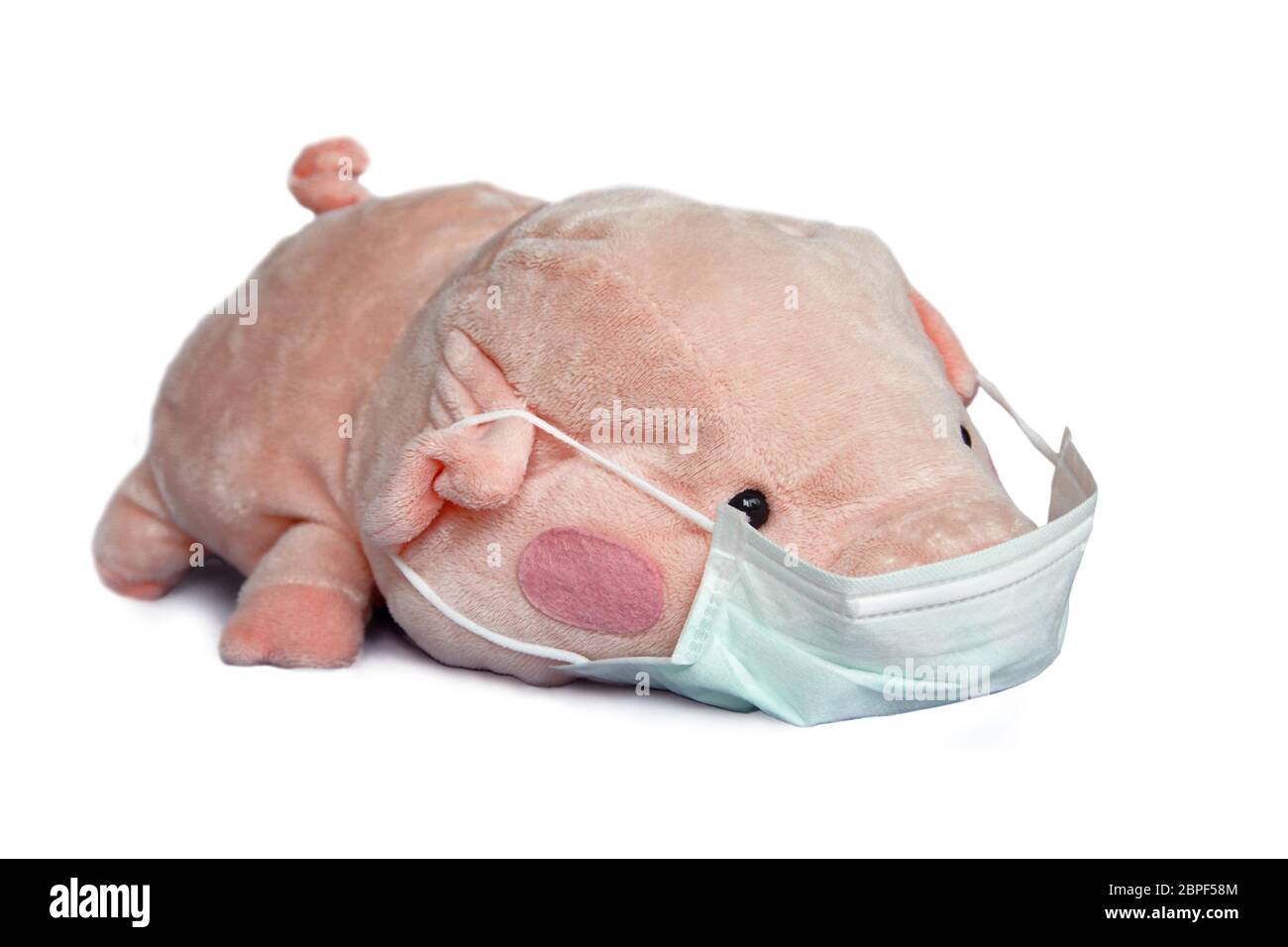 Stofftier Schwein mit einer medizinischen Gesichtsmaske isoliert auf weißem Hintergrund, Covid-19 Coronavirus Epidemie und Kinder-Konzept Stockfoto