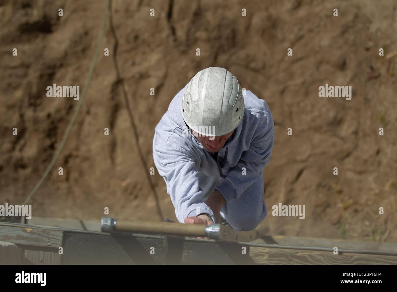 Ein männlicher Rettungsschwimmer klettert die Treppe hinauf. Ein Helfer in einem Schutzhelm ist Training. Stockfoto