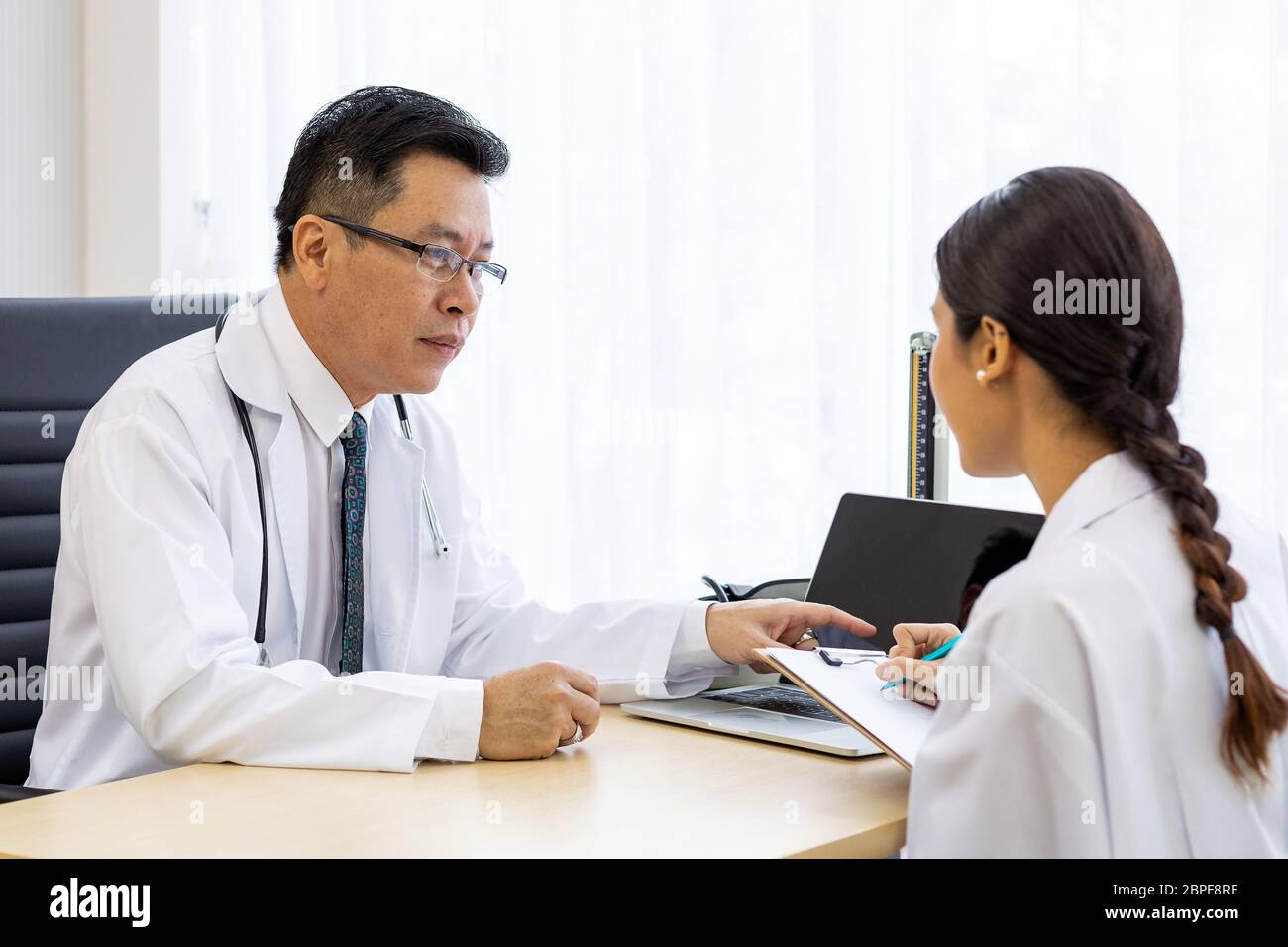 Zwei Ärzte im Krankenhaus die Diagnos des Patienten besprechen Stockfoto