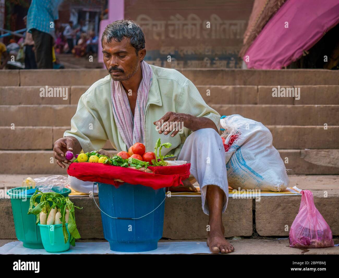 Varanasi, Indien - 11. November 2015. Ein Inder bereitet sich darauf vor, auf den Ghat-Stufen frisches Gemüse an Pilger und Touristen zu verkaufen. Stockfoto