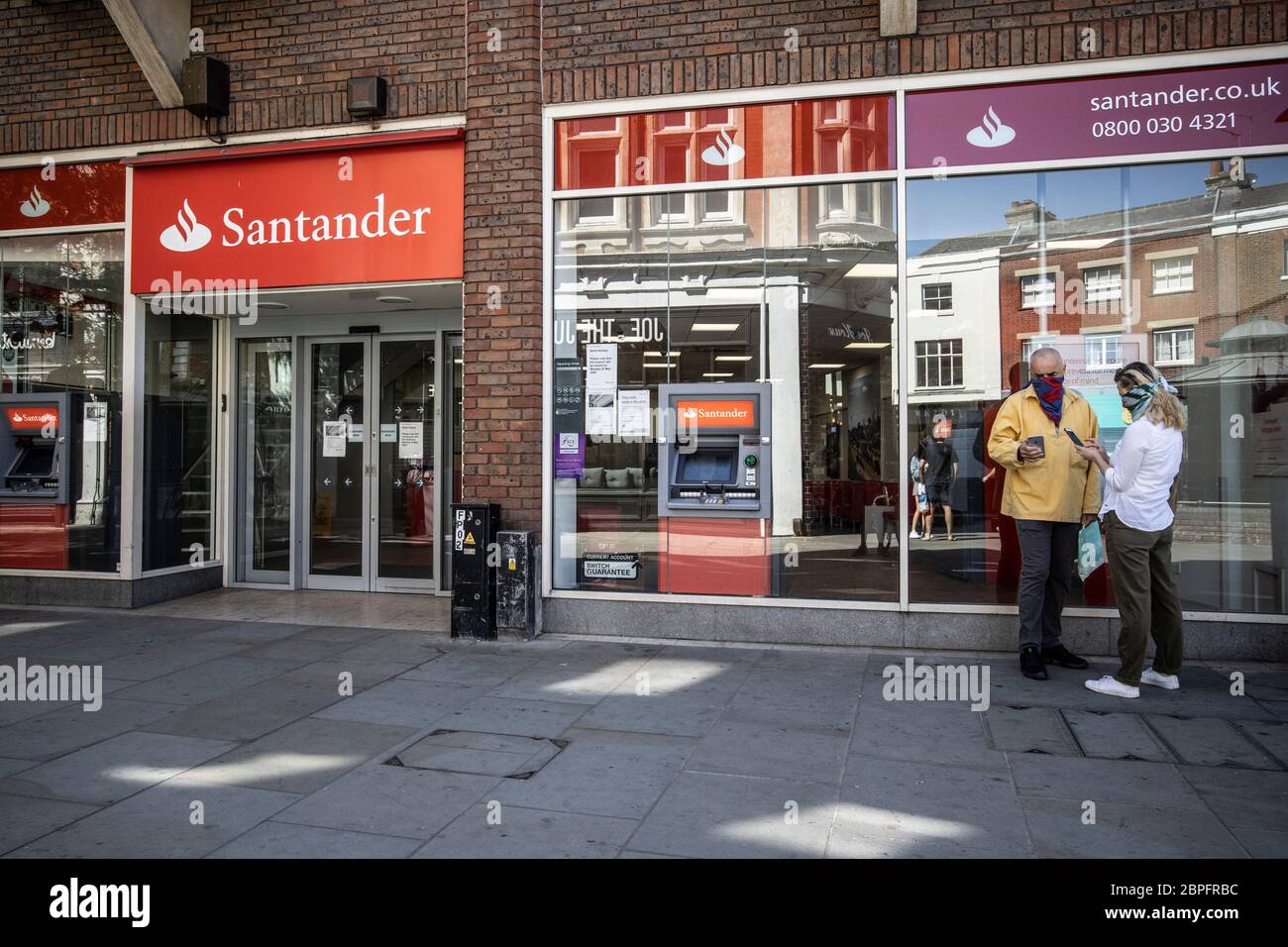 Menschen, die Gesichtsmasken tragen, vor einer Santander Bankfiliale, die Internet-Banking auf ihren Mobiltelefonen, Richmond upon Thames, Southwest London, Großbritannien Stockfoto