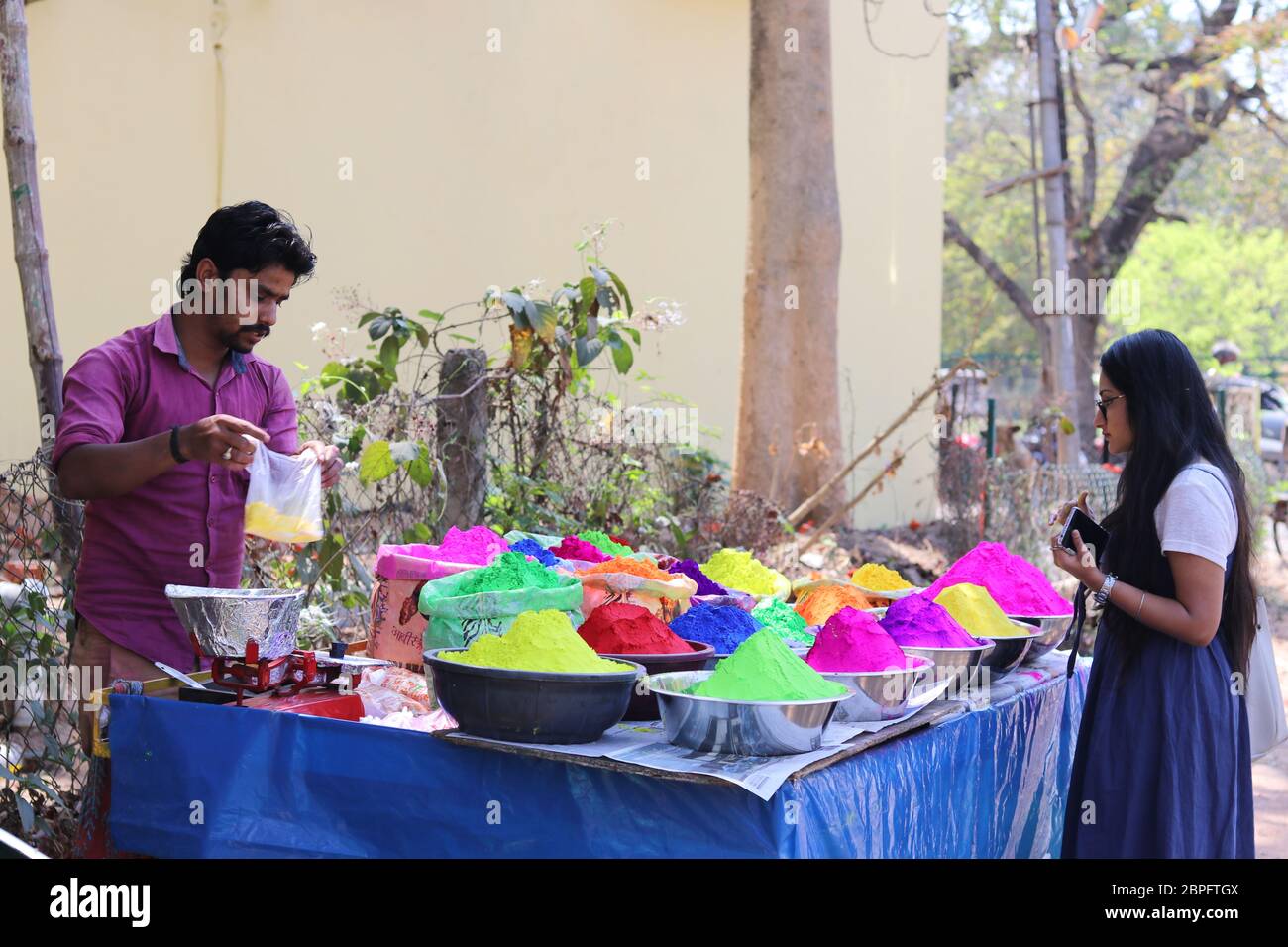 Ein Mädchen in Bolpur Street Market Stall Kauf Pulver trockene Farben auf Holi Festival Anlass. Holi ist berühmt Festival der Farben gefeiert alle indischen Stockfoto