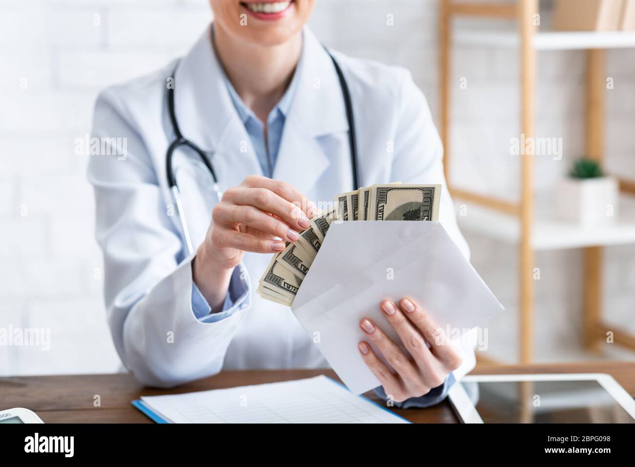 Teure Arznei. Lächelnder Arzt zählt Geld im Umschlag Stockfoto