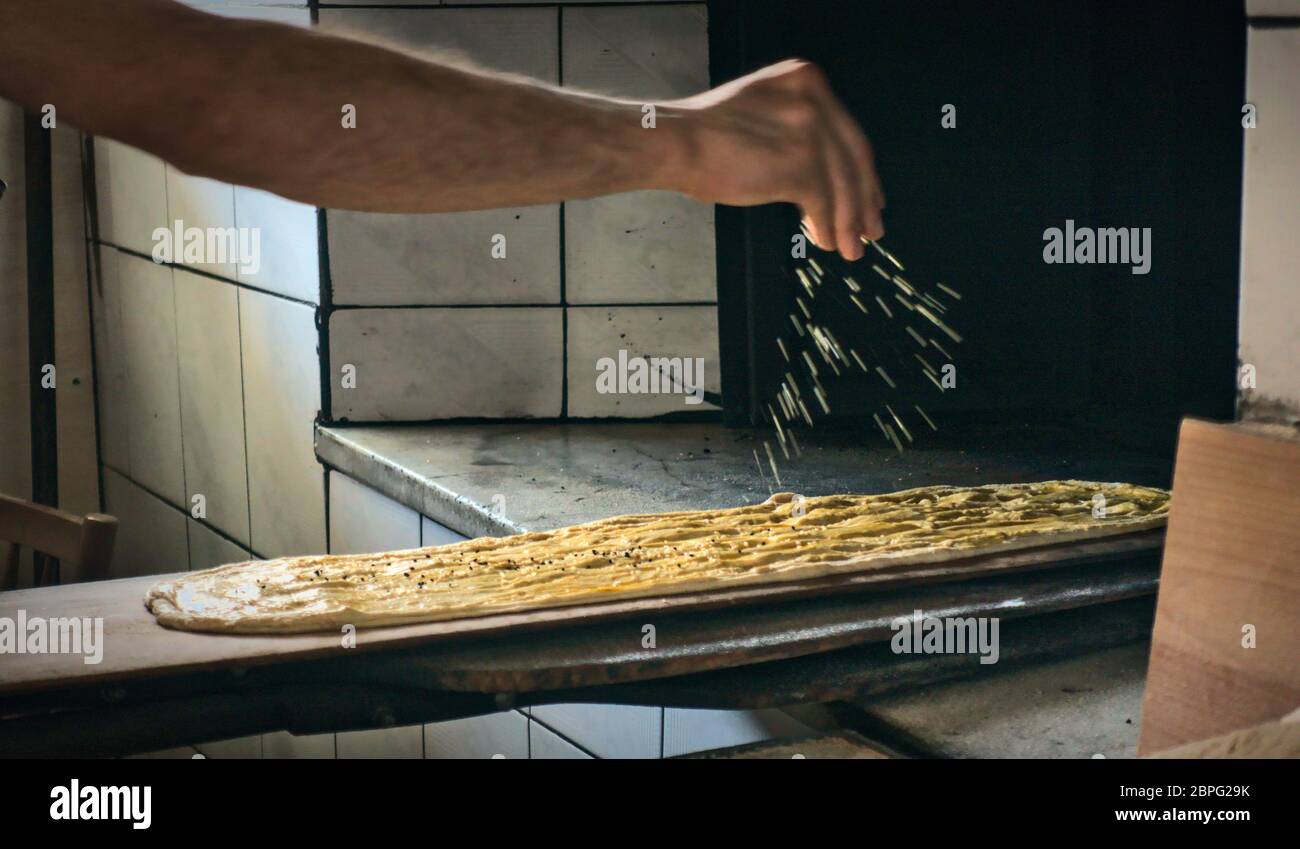 Türkisch-muslimischer Bäcker, der Sesam über den traditionellen ramadan-Brotmonat der muslime gießt Stockfoto