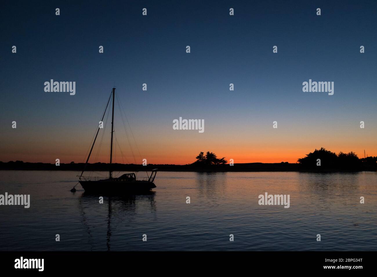 Ein kleines Segelboot mit einem Mast, das im Fluss bei Etel, einem alten Thunfischanglerstädtchen in Morbihan, Bretagne, an der Atlantikküste Frankreichs, verankert ist Stockfoto