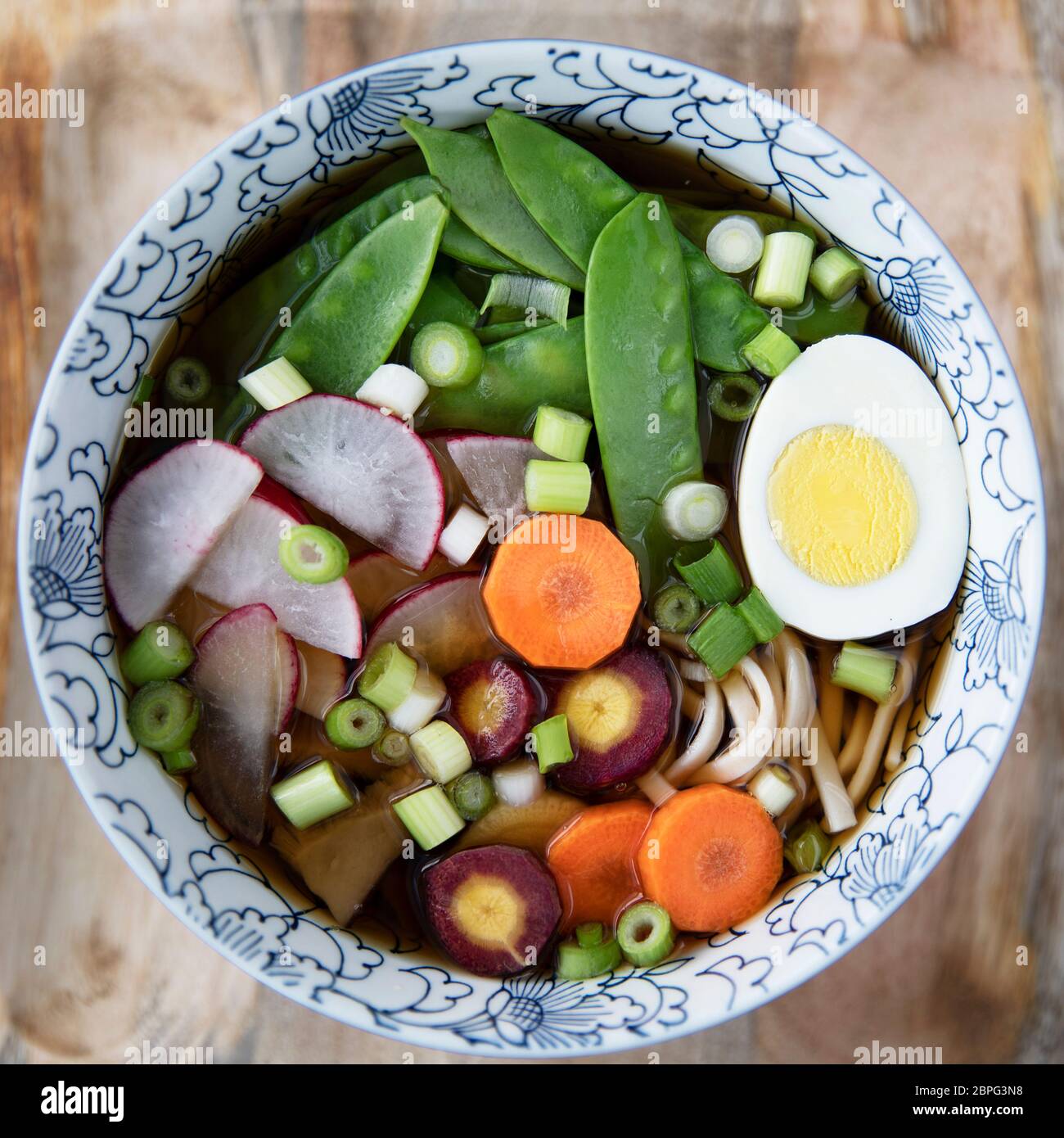 Bunte Schüssel von udon Suppe mit frischem Gemüse und hart gekochtem Ei. Flach, quadratisch Stockfoto