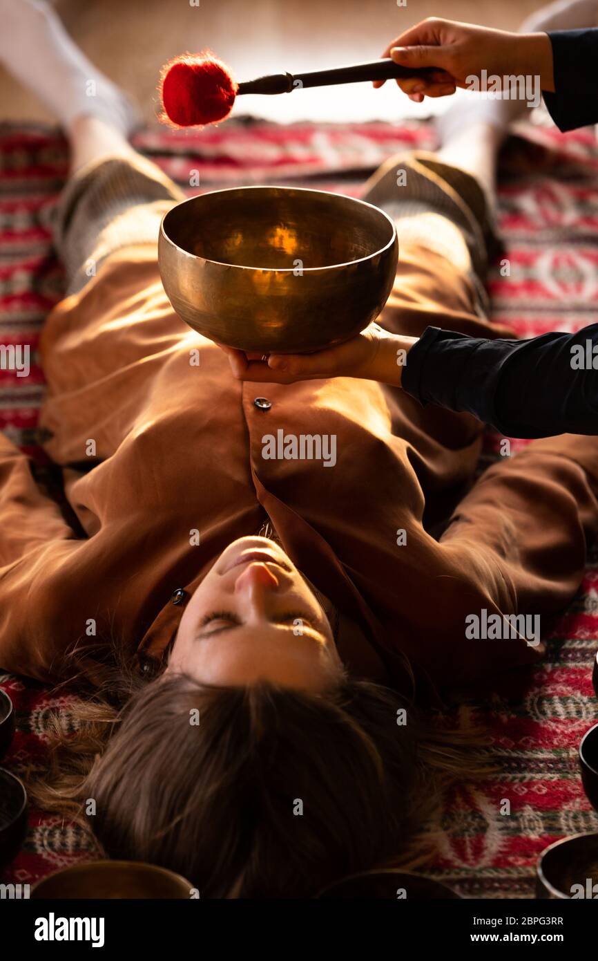 Frau macht entspannende Massage, Meditation, Klangtherapie mit tibetischen Klangschalen. Stressabbau. Selektiver Fokus. Draufsicht. Stockfoto