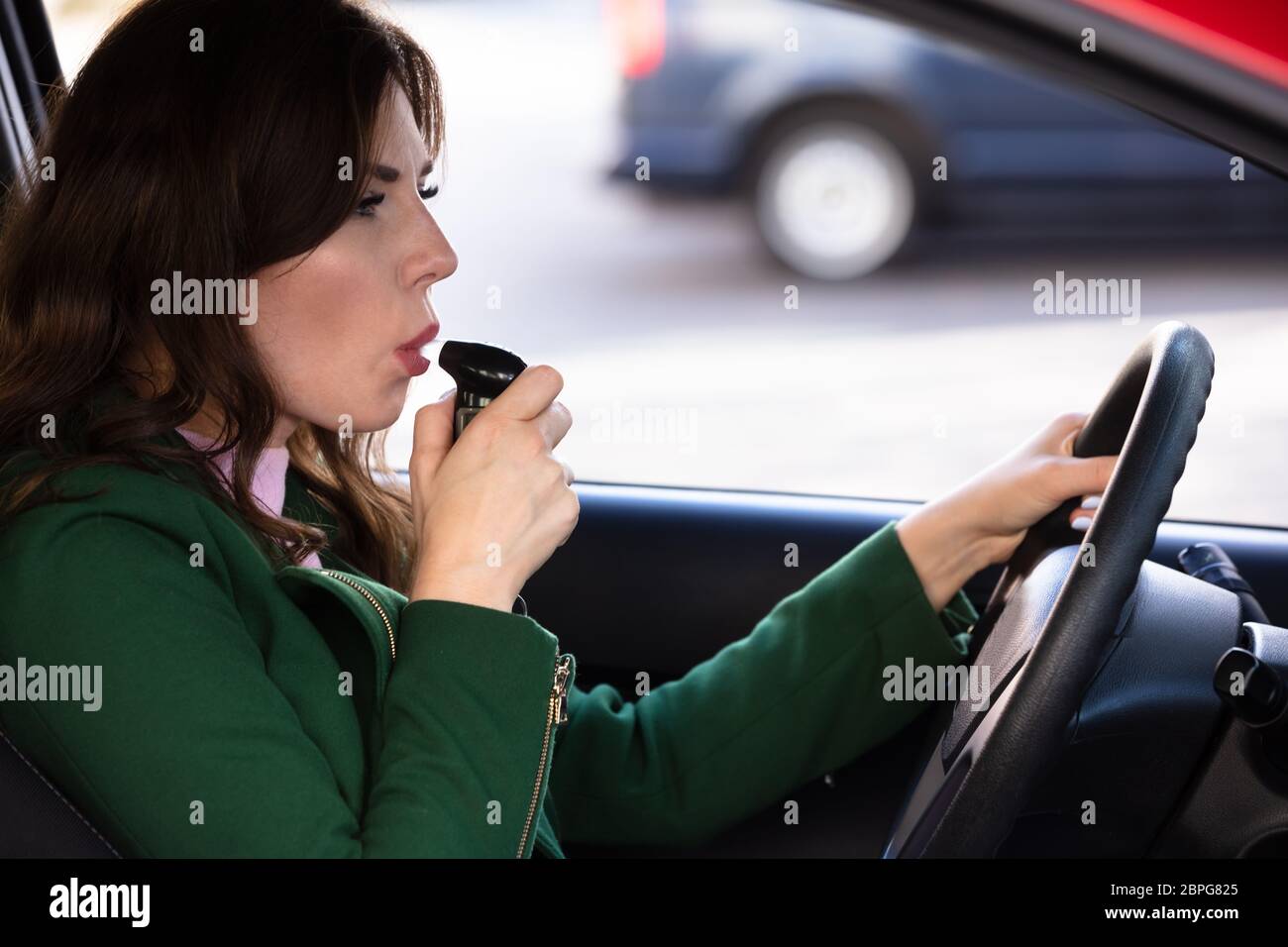 Seitliche Sicht auf eine schöne junge Frau sitzt im Auto, Alkohol Test Stockfoto