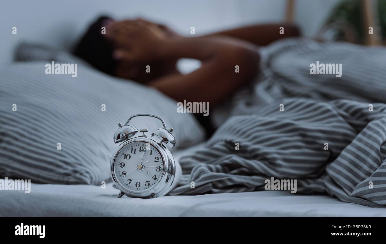 afroamerikanische Frau, die an Schlaflosigkeit leidet, im Bett ohne Schlaf liegend. Stockfoto