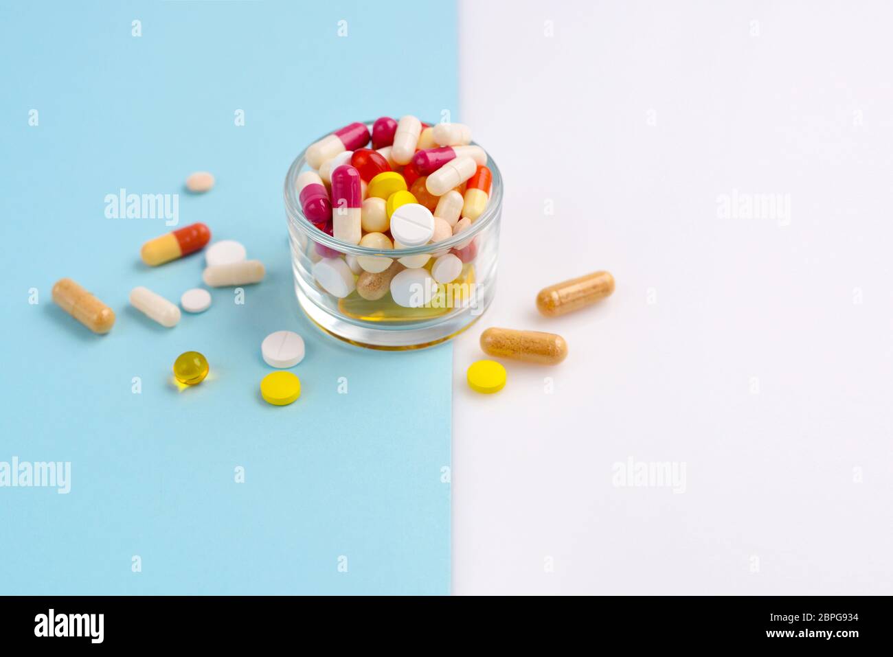 Verschiedene pharmazeutische Medizin Pillen, Tabletten und Kapseln in einem Glas auf blauem und weißem Hintergrund Stockfoto
