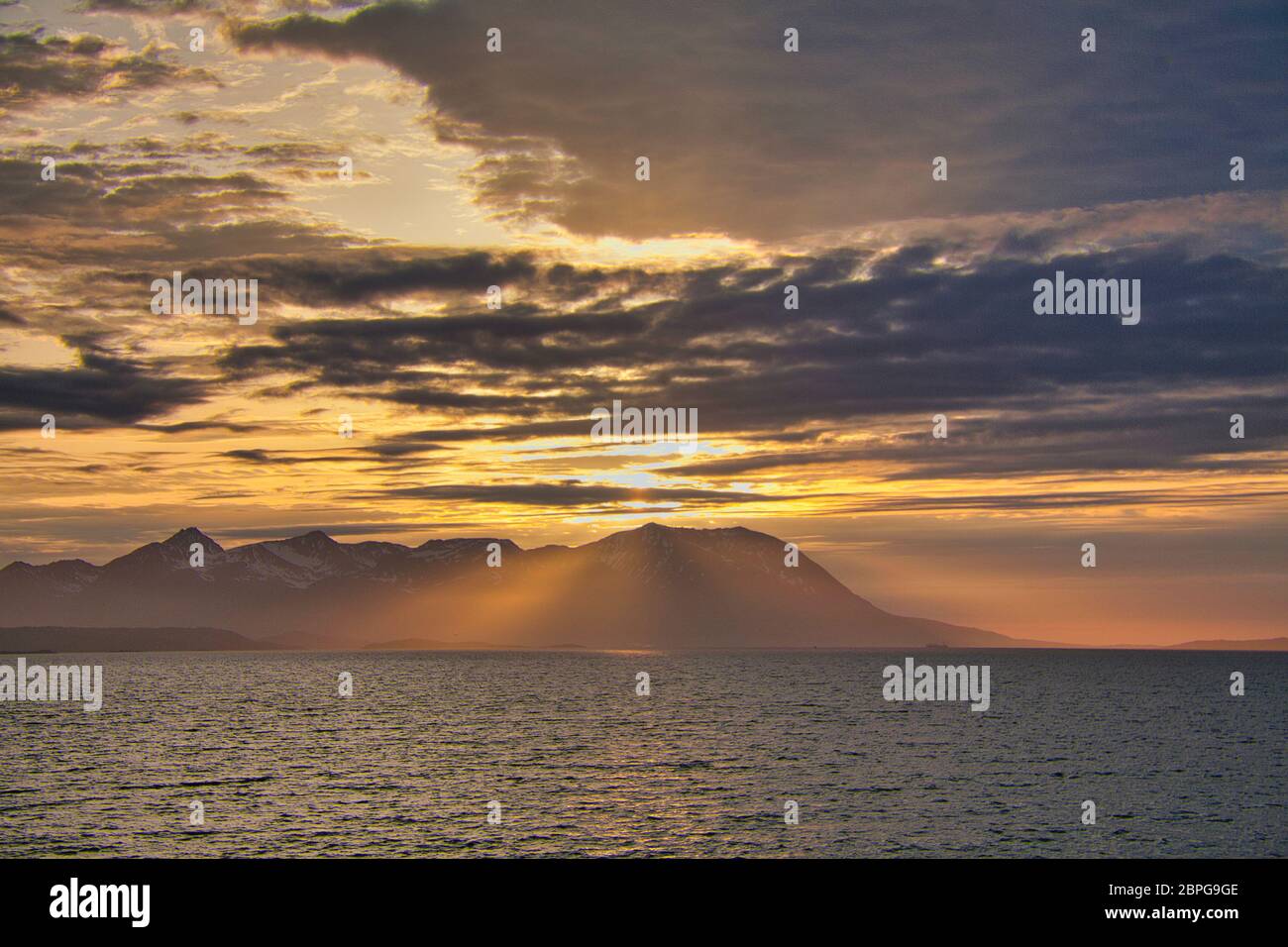 Inseln vor der Westküste Nordnorwegens im Licht der Mitternachtssonne mit einem dramatischen Himmel, Wolken und Sonnenstrahlen, die durchscheinen Stockfoto