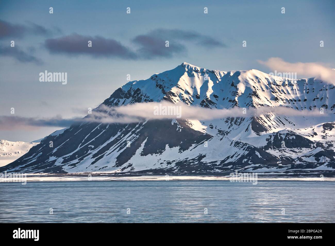 Bergszene mit schneebedeckten Gipfeln, die in Wolken bei Spitzbergen, Svalbard, Nordnorwegen, umraht sind Stockfoto