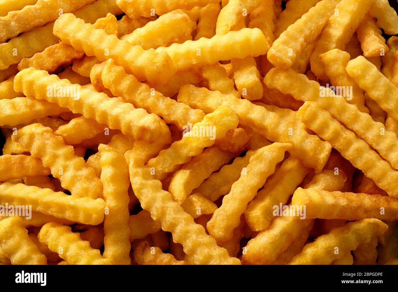 Nahaufnahme Hintergrund der Crinkle cut knusprige Golden fried Potato Chips, Pommes frites, Pommes Frites Inn a full frame anzeigen Stockfoto