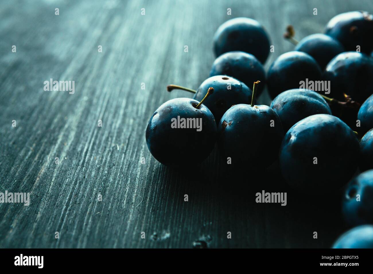 Viele frische Pflaumen auf schwarzem Hintergrund. Stockfoto