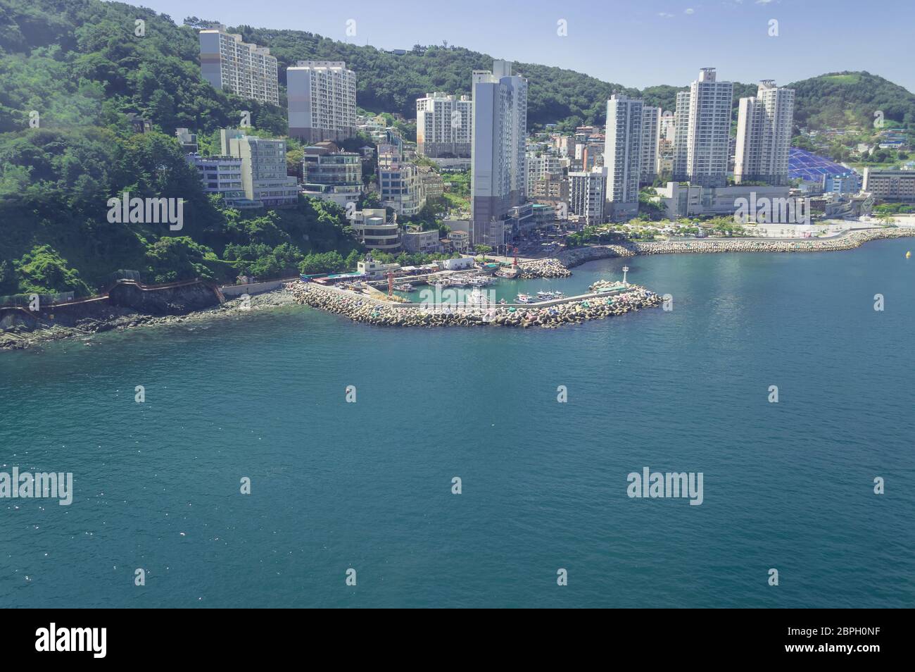 Blick von oben auf den Yachthafen mit Pier und Stadtbild von Busan mit Bergen in der Nähe von Songdo Strand Stockfoto