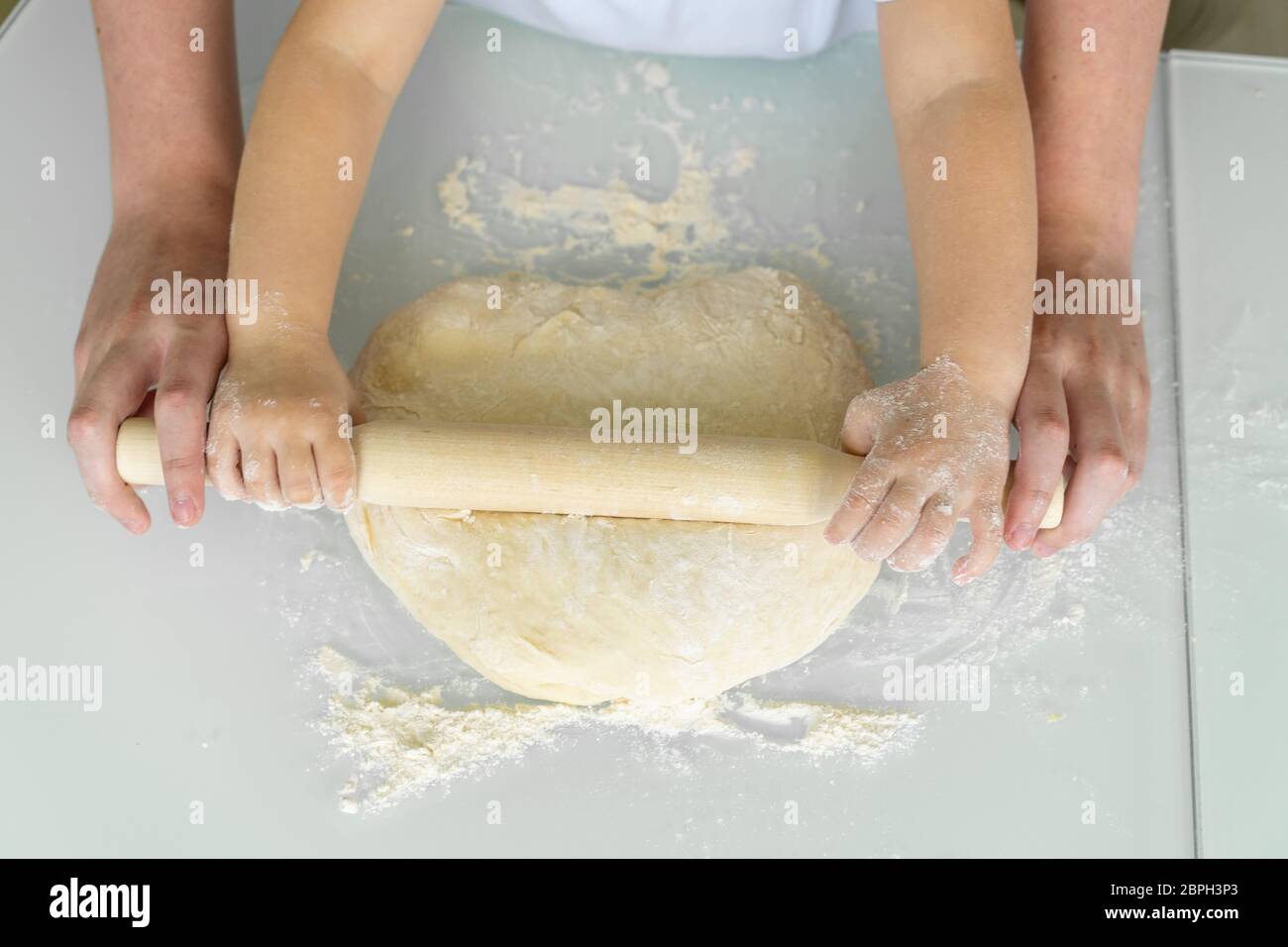 Glückliche Familie in der Küche. Mutter und Tochter Rollen den Teig mit einem Nudelholz aus. Urlaub und Familie Freizeitkonzept. Stockfoto