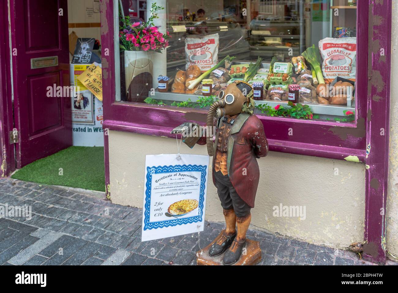 Clonakilty, West Cork, Irland. 19. Mai 2020. Viele Menschen tragen während der Covid-19 Pandemie Gesichtsmasken, sogar Statuen. Arthur die Statue wurde heute mit einer Gasmaske vor Scullys Metzgerei in Clonakilty gesichtet. Credit: AG News/Alamy Live News Stockfoto