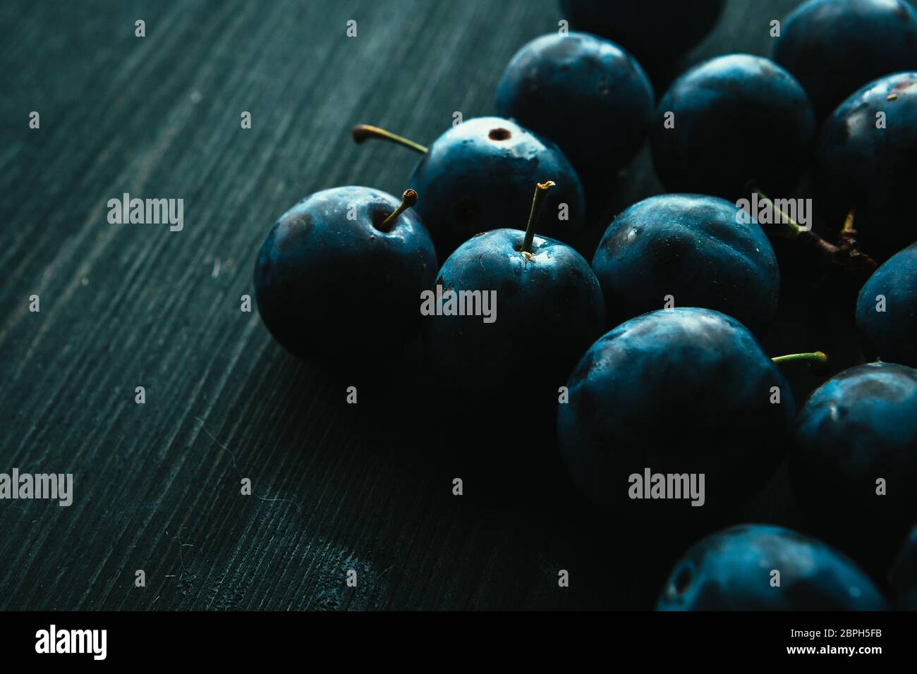 Viele frische Pflaumen auf schwarzem Hintergrund. Stockfoto