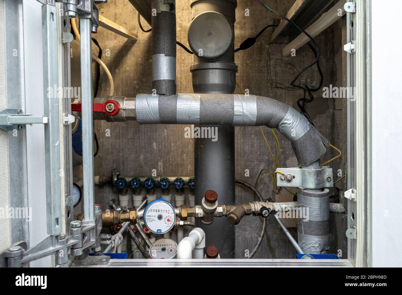 Schalten Sie heißes Wasser. Sanitär-Schrank. Wasserzähler, Kollektor, Wasserdrucksensor Stockfoto