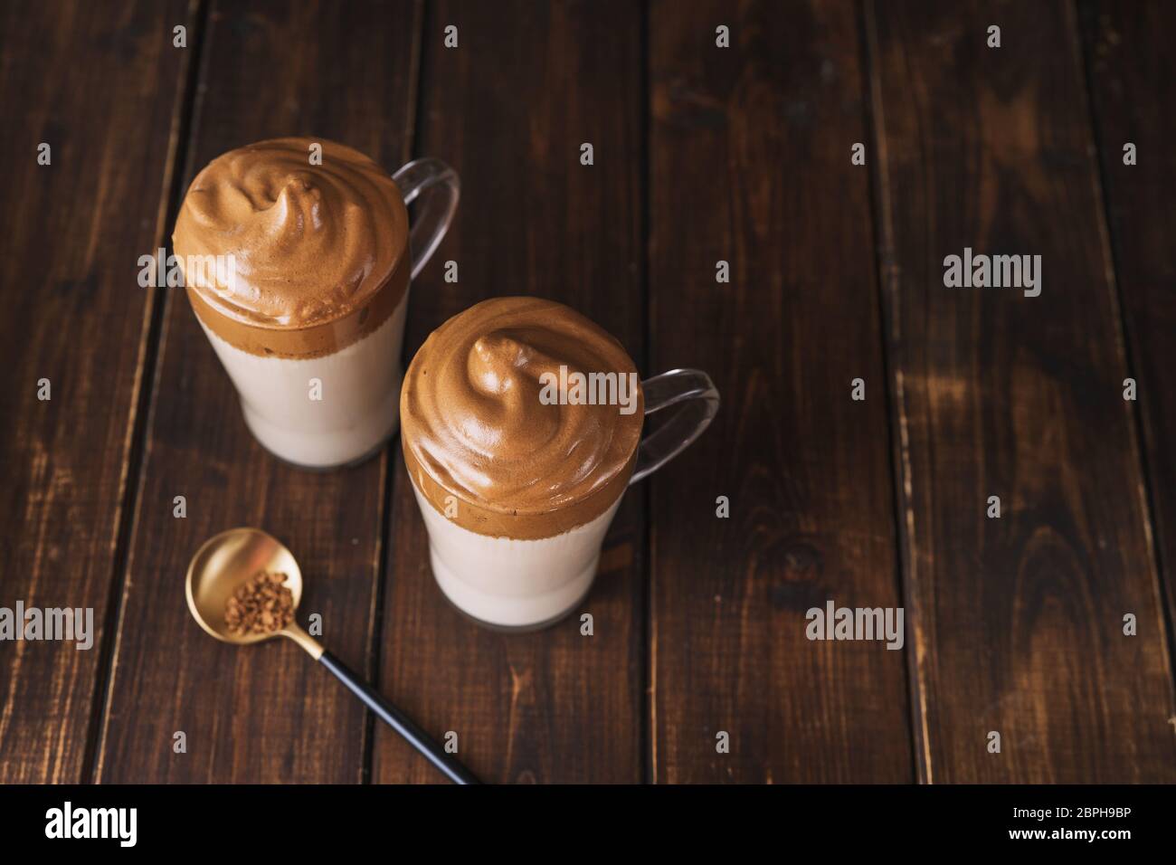 Draufsicht von zwei Gläsern mit berühmten Kaffee Dalgona auf dunklem Holztisch Stockfoto