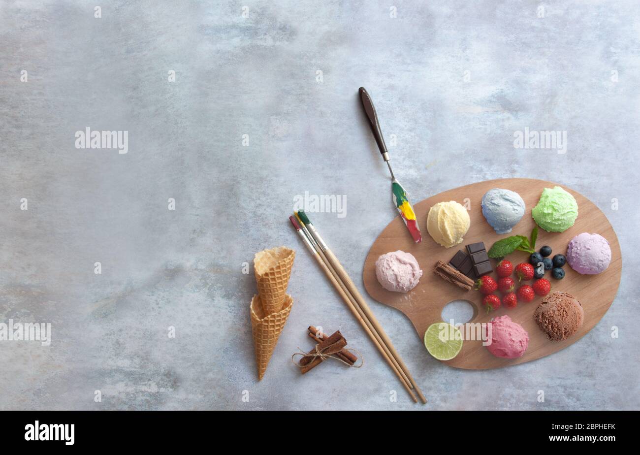 Verschiedene Eisbecher auf einer Malerpalette mit Zutaten in der Mitte Stockfoto